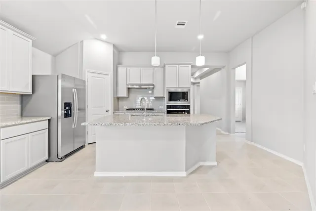 a large kitchen with white cabinets and stainless steel appliances