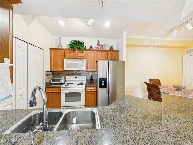 a kitchen with stainless steel appliances granite countertop a refrigerator a stove and a sink with wooden floor