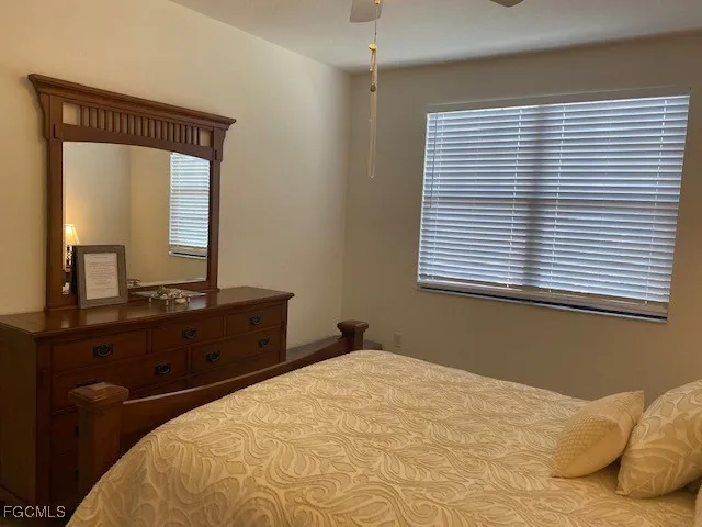 a bedroom with a bed windows and mirror