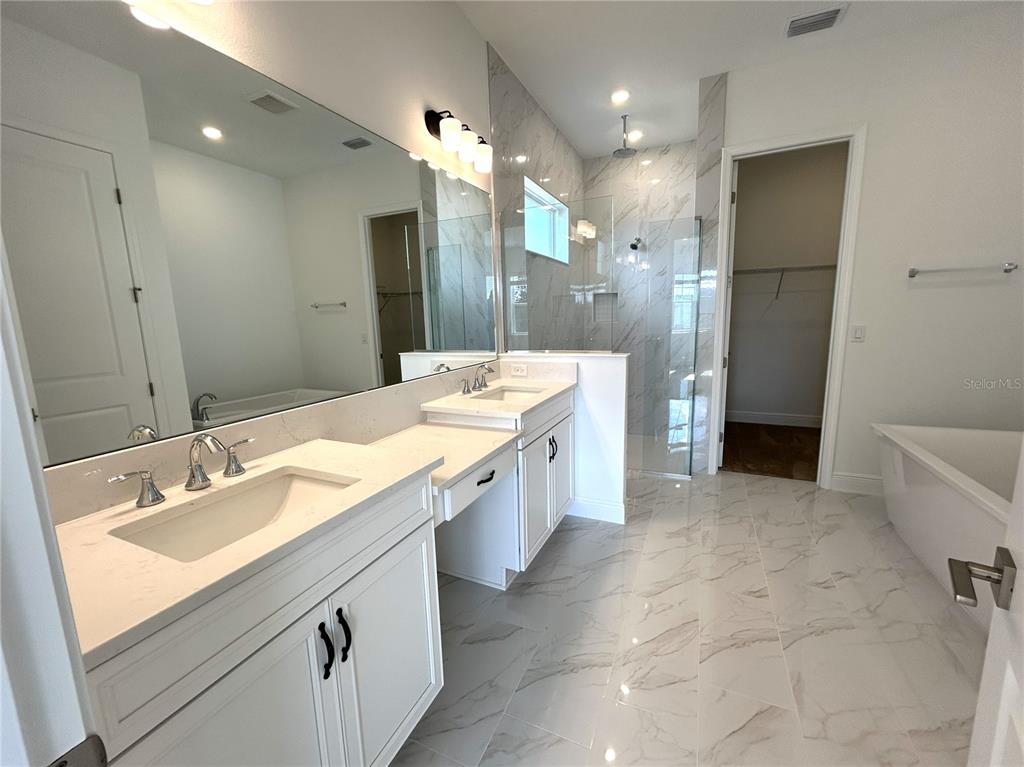 16017 Volterra Point Bella Collina, FL 34756 - Photo 23 of 30 a large bathroom with a double vanity sink a large mirror and a shower