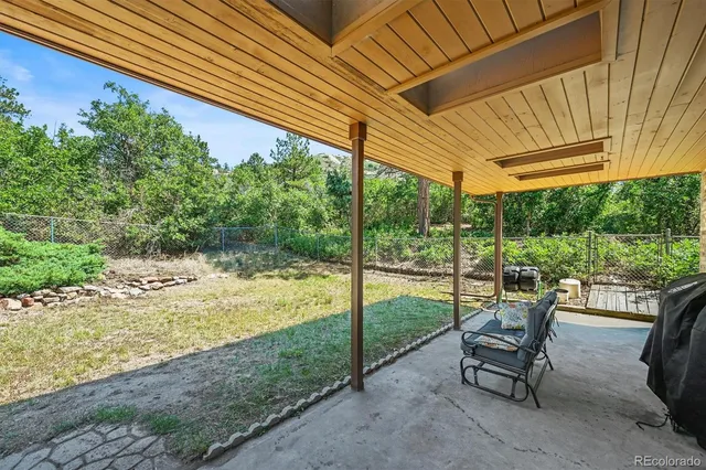 a view of a patio with table and chairs and floor to ceiling window next to a yard