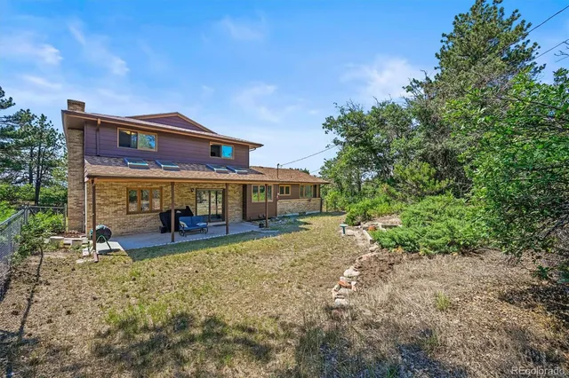 a view of a big house with large trees and plants
