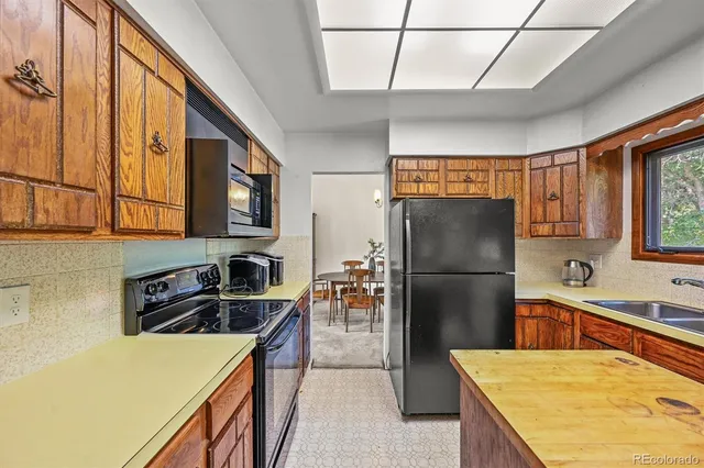 a kitchen with stainless steel appliances granite countertop a refrigerator a stove and a sink with wooden cabinets
