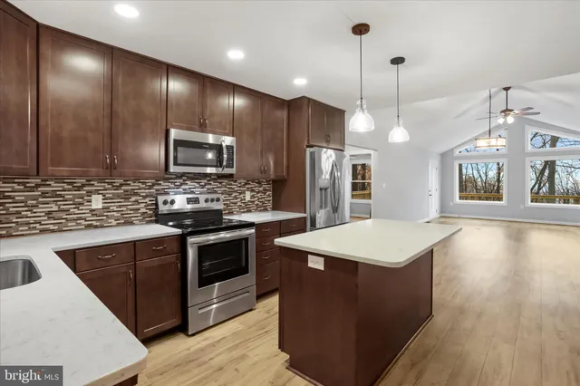 a kitchen with kitchen island a sink stainless steel appliances and cabinets