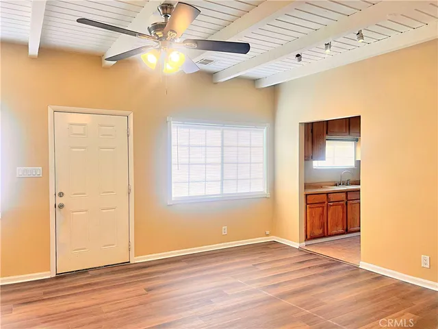 a view of an empty room with window and wooden floor