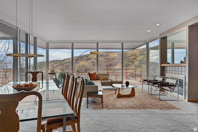1856 Fort Canyon Road Alpine, UT 84004 - Photo 8 of 49 Open-concept living space featuring floor-to-ceiling windows, a glass-top dining table, recessed lighting, a fireplace with a tile surround, and a balcony with a railing overlooking mountains