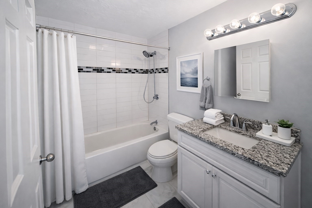 7 Gibbs Street, Unit 7 Worcester, MA 01607 - Photo 4 of 20 a bathroom with a granite countertop sink a toilet a mirror and shower