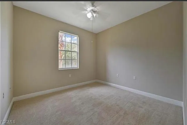 an empty room with windows and ceiling fan