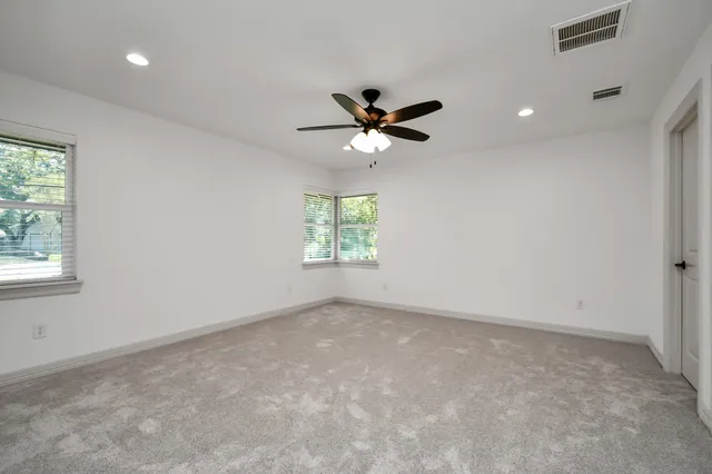 an empty room with windows and fan