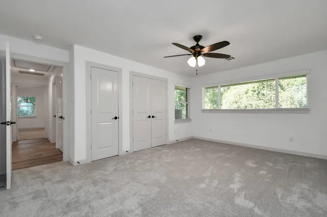 an empty room that has a window and a ceiling fan