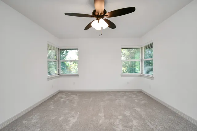 an empty room with a window and a fan
