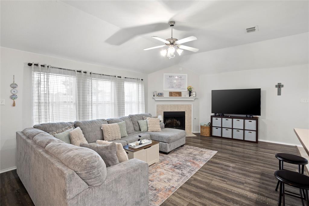 213 Arabian Road Waxahachie, TX 75165 - Photo 17 of 29 Living area featuring a ceiling fan, vaulted ceiling, dark wood-type flooring, and a tiled fireplace