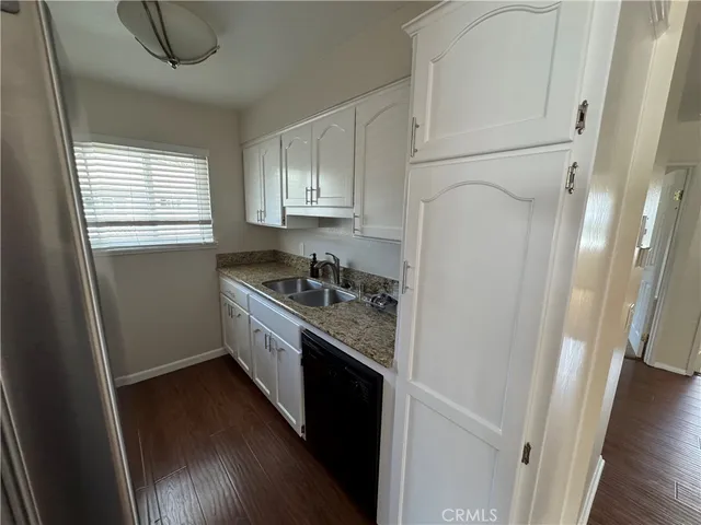 a kitchen with stainless steel appliances granite countertop a refrigerator a sink dishwasher a stove and white countertops with wooden floor