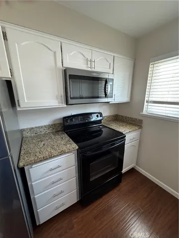 a kitchen with granite countertop cabinets stainless steel appliances and a window