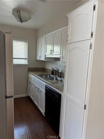a kitchen with stainless steel appliances white cabinets and wooden floor