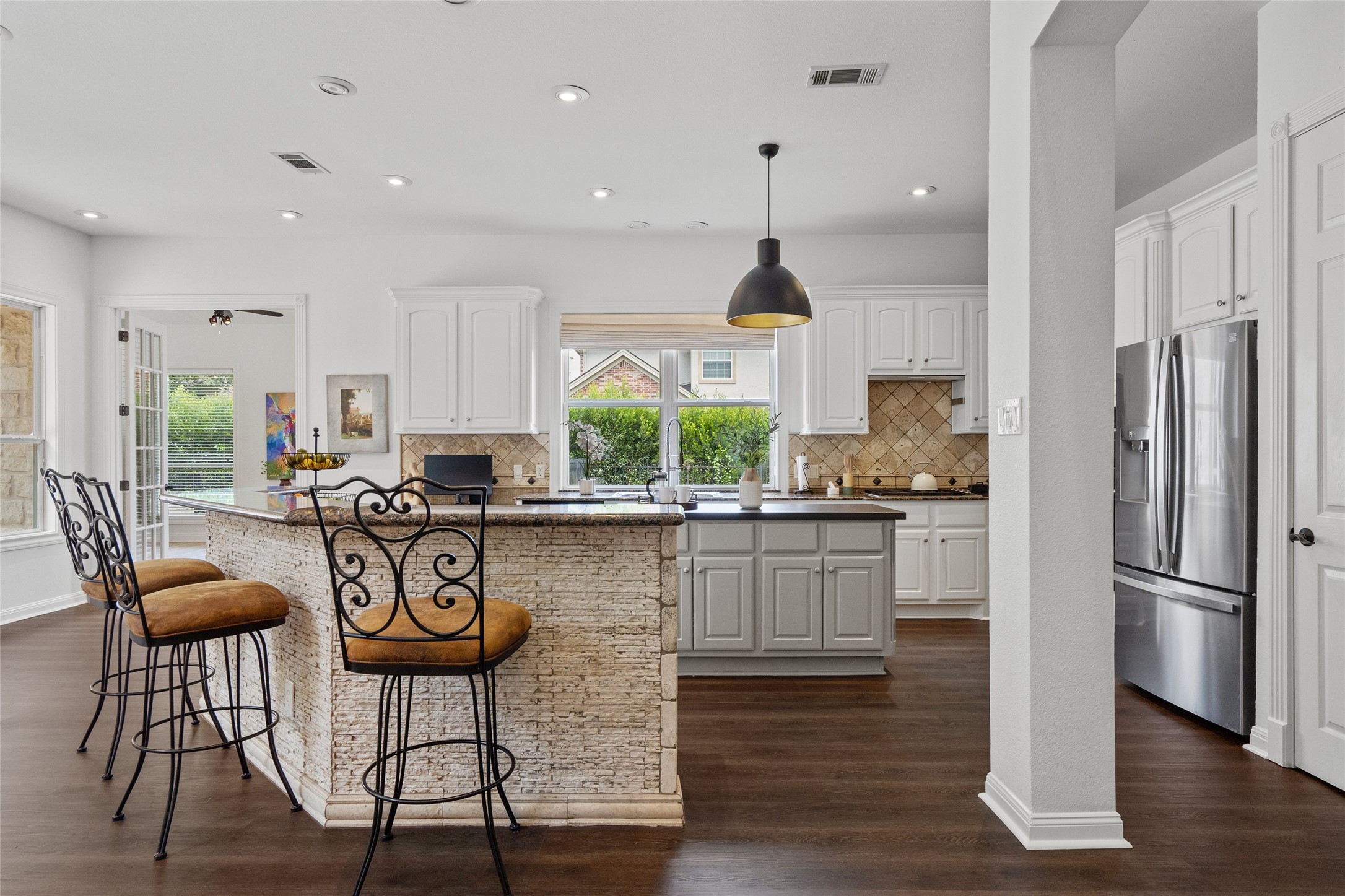 4313 Rio Robles Drive Austin, TX 78746 - Photo 11 of 40 A well-lit kitchen with dark wood floors and a convenient breakfast bar.
