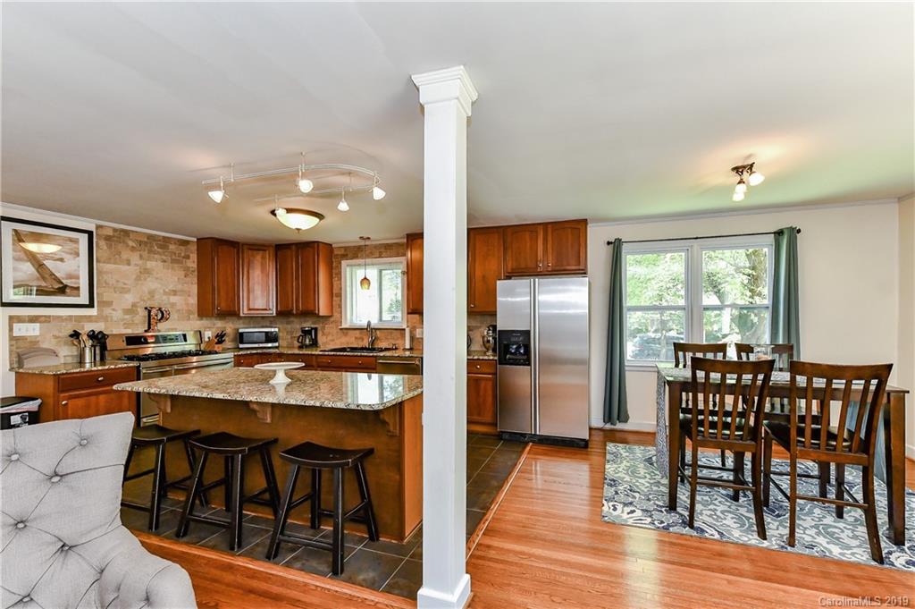 526 Scaleybark Road Charlotte, NC 28209 - Photo 6 of 37 a kitchen with stainless steel appliances granite countertop wooden floor dining table and chairs