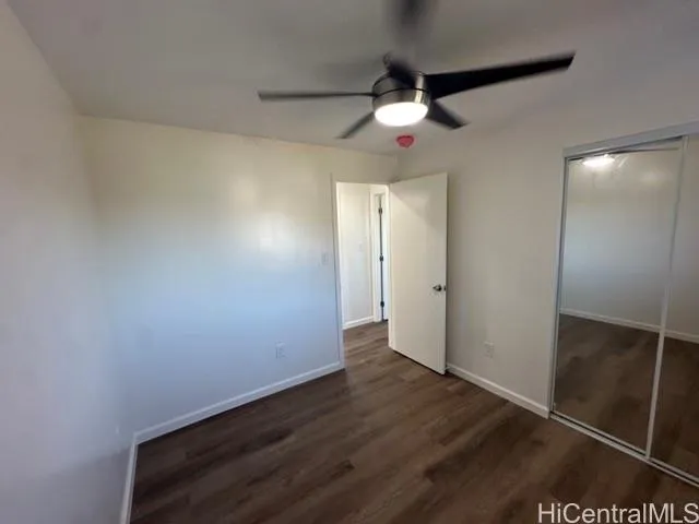 an empty room with wooden floor and fan