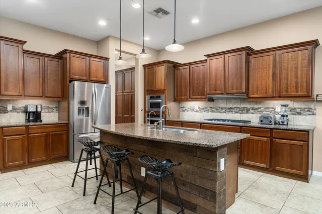 a kitchen with stainless steel appliances granite countertop table chairs sink refrigerator and cabinets