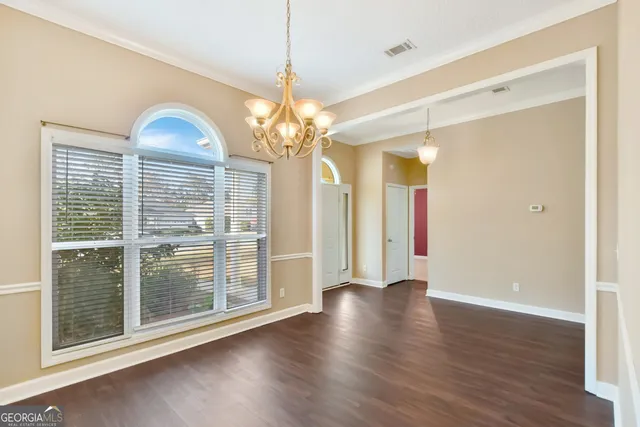 a view of a livingroom with wooden floor staircase and a kitchen