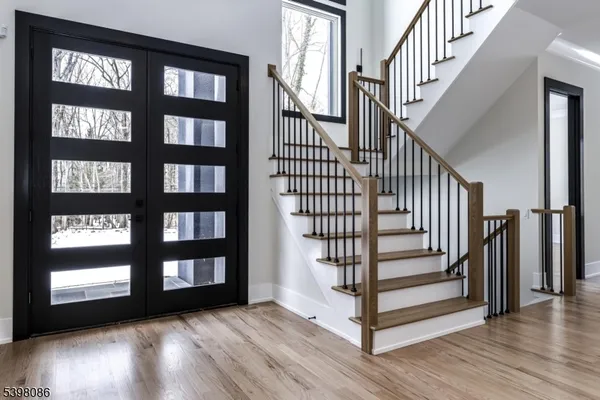 a view of front door with staircase and wooden floor