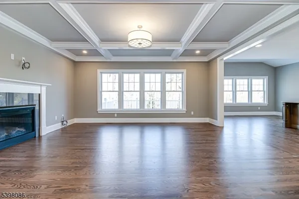 an empty room with wooden floor fireplace and windows