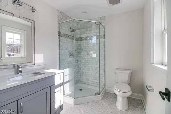 a bathroom with a shower sink vanity mirror and toilet
