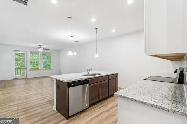 a kitchen with stainless steel appliances granite countertop a sink a stove and a wooden floors