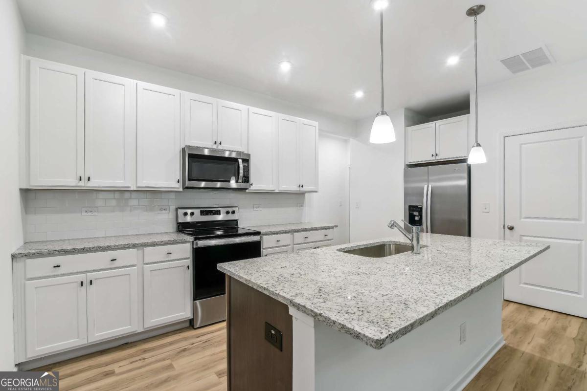 1545 Salinger Court, Unit 1545 Stockbridge, GA 30281 - Photo 8 of 26 a kitchen with kitchen island granite countertop stainless steel appliances and white cabinets