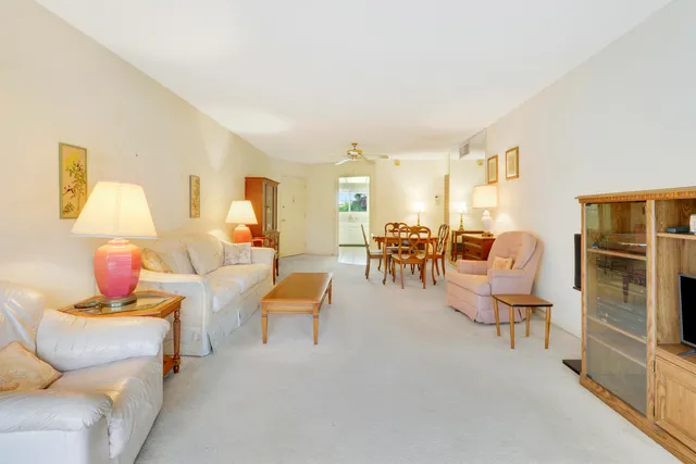 a living room with furniture kitchen view and a wooden floor