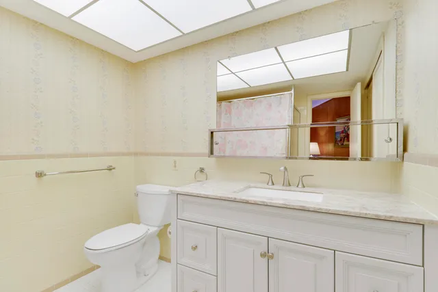 a bathroom with a granite countertop toilet sink and mirror