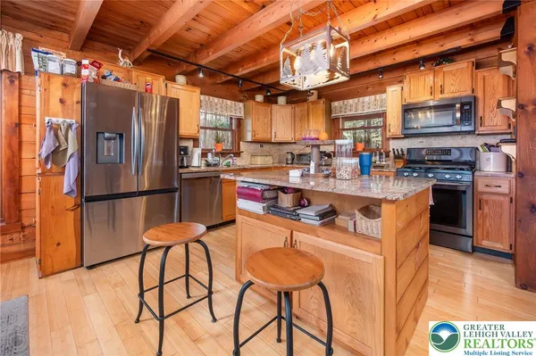 a kitchen with stainless steel appliances granite countertop a table chairs refrigerator and a microwave
