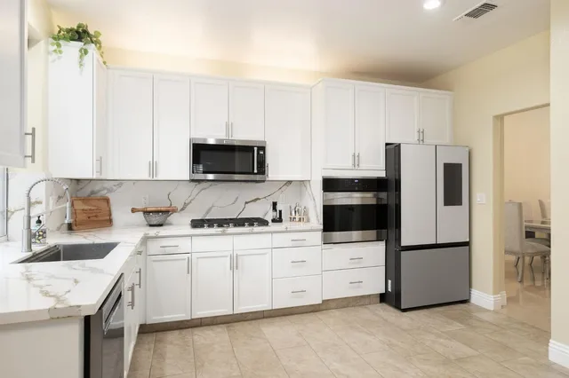 a kitchen with stainless steel appliances granite countertop a refrigerator sink and white cabinets