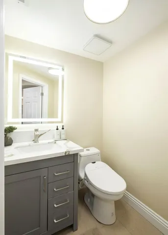 a bathroom with a toilet sink vanity and mirror