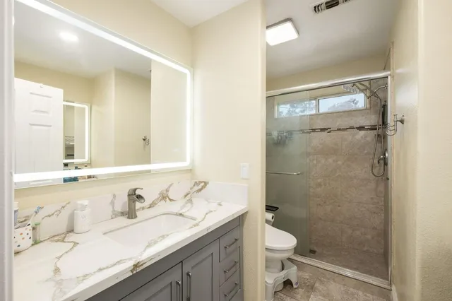 a bathroom with a granite countertop sink toilet and shower