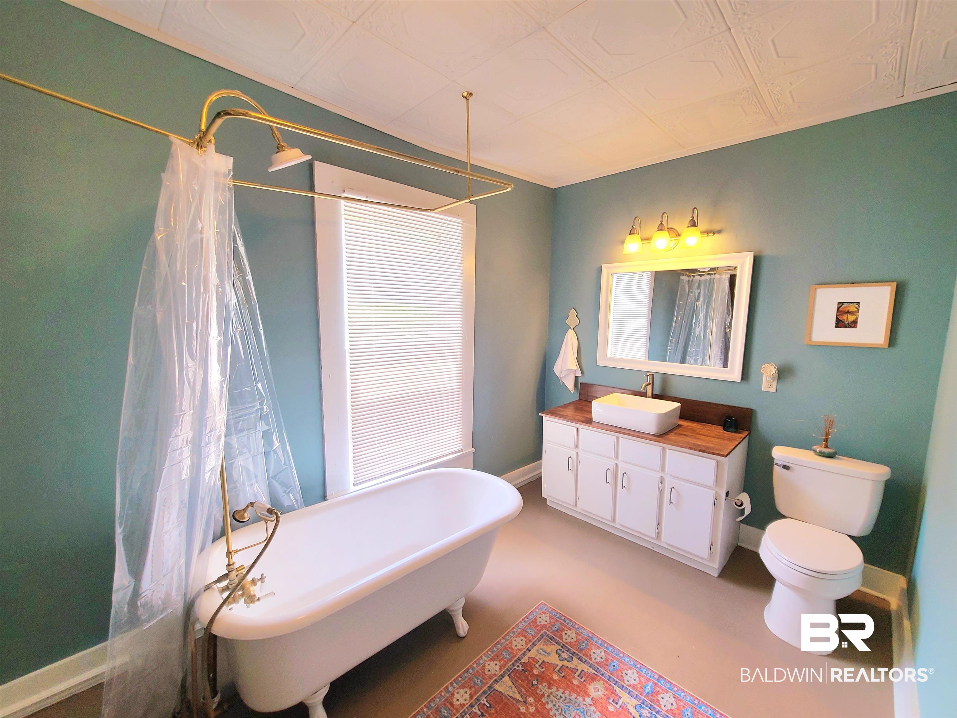 112 Espejo Street Mobile, AL 36604 - Photo 11 of 20 Bathroom with vanity, a freestanding tub, toilet, baseboards, and a shower with shower curtain