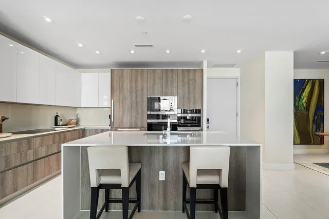 a kitchen with kitchen island granite countertop a dining table chairs and white stainless steel appliances
