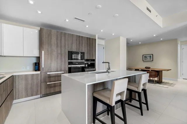 a kitchen with stainless steel appliances kitchen island granite countertop a table and chairs in it
