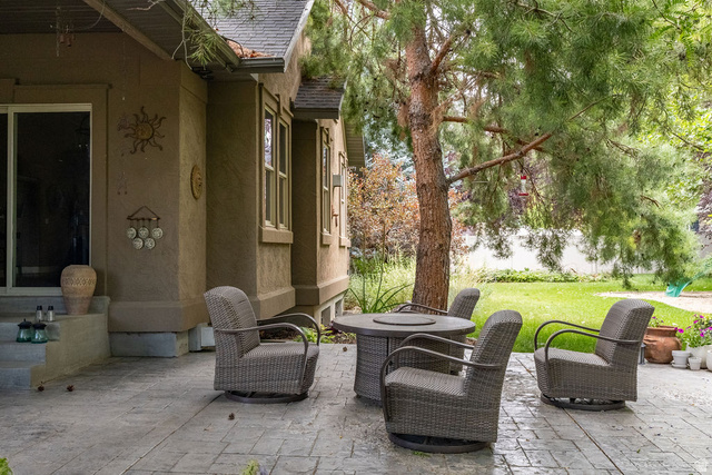 288 525 South Providence, UT 84332 - Photo 46 of 71 Stamped concrete patio featuring a mature tree, adjacent to a stucco exterior with multiple windows and a sliding glass door