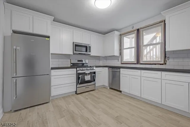 a kitchen with white cabinets and stainless steel appliances