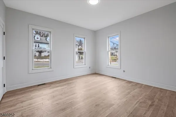 a view of an empty room with window and wooden floor