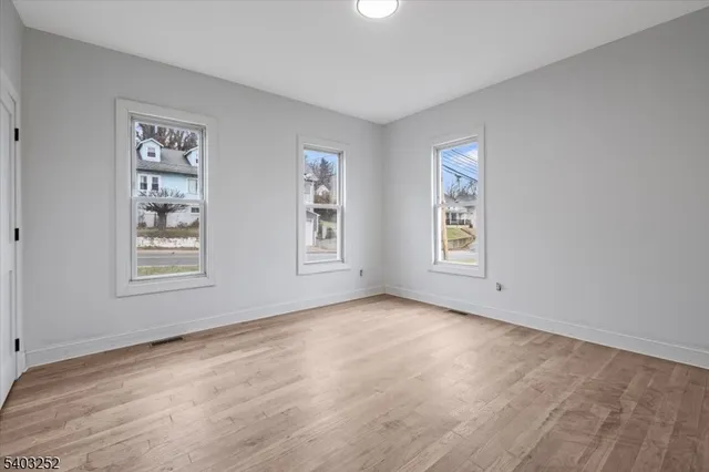 a view of an empty room with window and wooden floor
