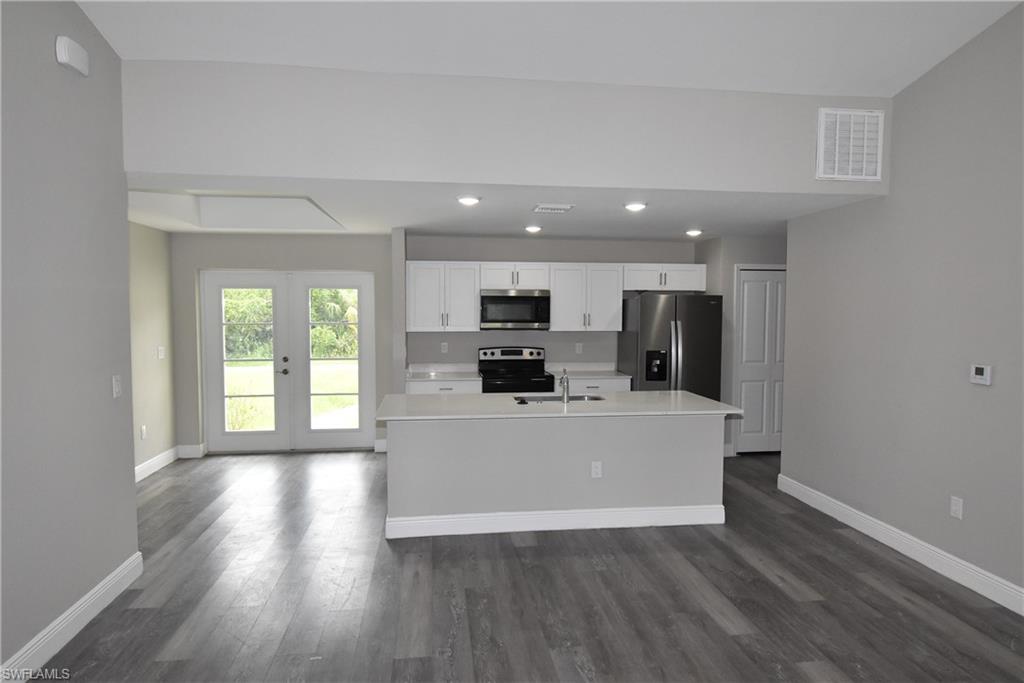 2140 Yalta Terrace North Port, FL 34286 - Photo 4 of 26 Kitchen with appliances with stainless steel finishes, light countertops, french doors, dark wood-style floors, and white cabinetry