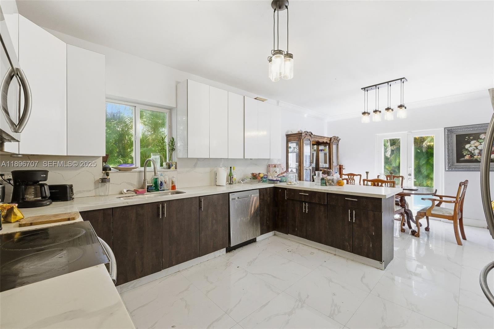 401 Southwest 28th Road Miami, FL 33129 - Photo 14 of 45 a kitchen with stainless steel appliances granite countertop a refrigerator a sink dishwasher a stove and a dining table with wooden floor