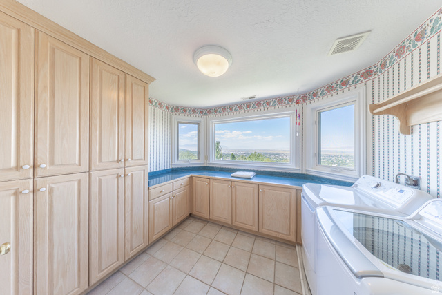 144 Bountiful Boulevard Bountiful, UT 84010 - Photo 23 of 28 Laundry area featuring wallpapered walls, washing machine and clothes dryer, cabinet space, light tile patterned flooring, and a textured ceiling