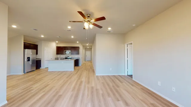 a view of a kitchen with kitchen island a sink wooden floor and stainless steel appliances