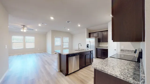 a kitchen with stainless steel appliances granite countertop a stove top oven a sink dishwasher and a refrigerator with wooden floor