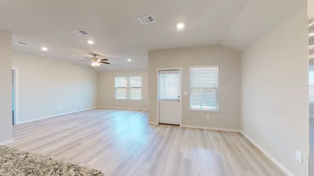 an empty room with wooden floor and windows
