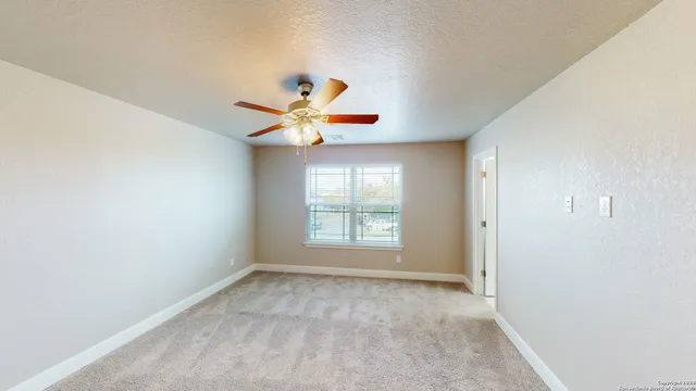 an empty room with a window and a chandelier fan
