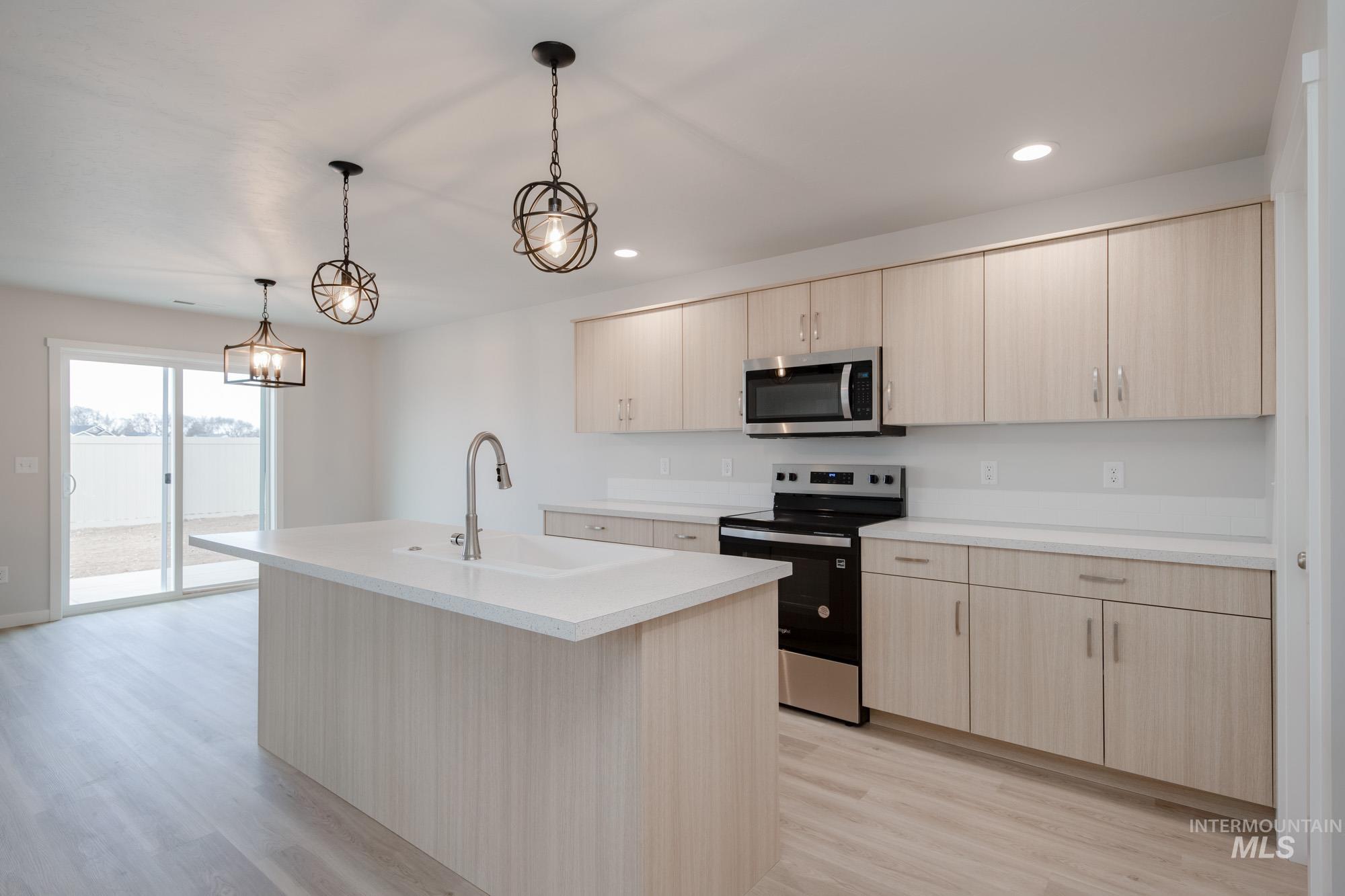 3089 South Maple Rnch Way Nampa, ID 83686 - Photo 5 of 22 Kitchen featuring appliances with stainless steel finishes, light wood-type flooring, light brown cabinets, a kitchen island with sink, and recessed lighting